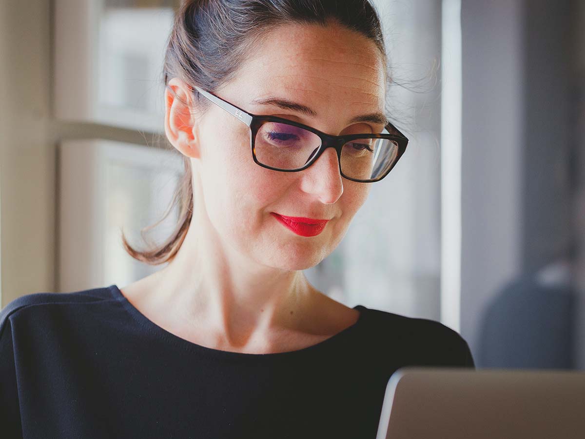 woman looking at computer screen with glasses on